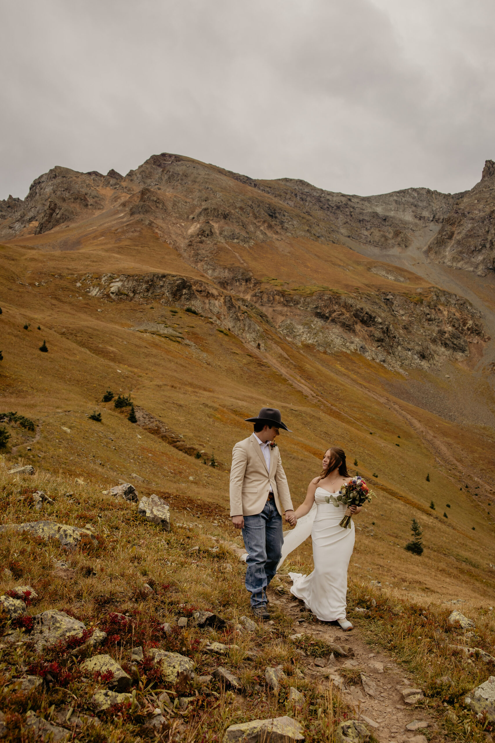 Bridal couple walking down mountain.