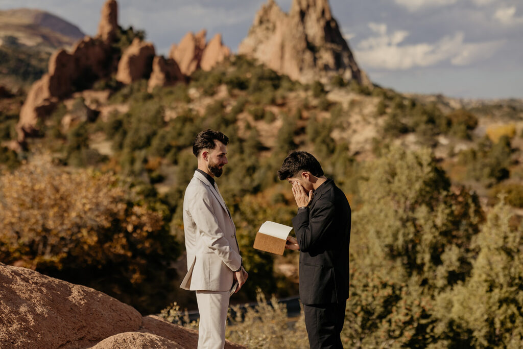 LGBTQ couple reading vows to each other with Garden of the Gods in background.