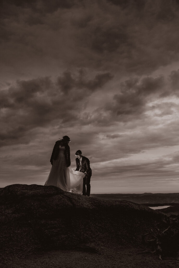 Groom adjusting bride's dress while wearing a headlamp before the sun rises.