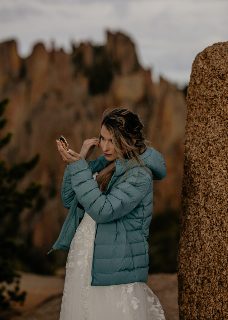 Bride looking into compact mirror getting ready for sunrise elopement.