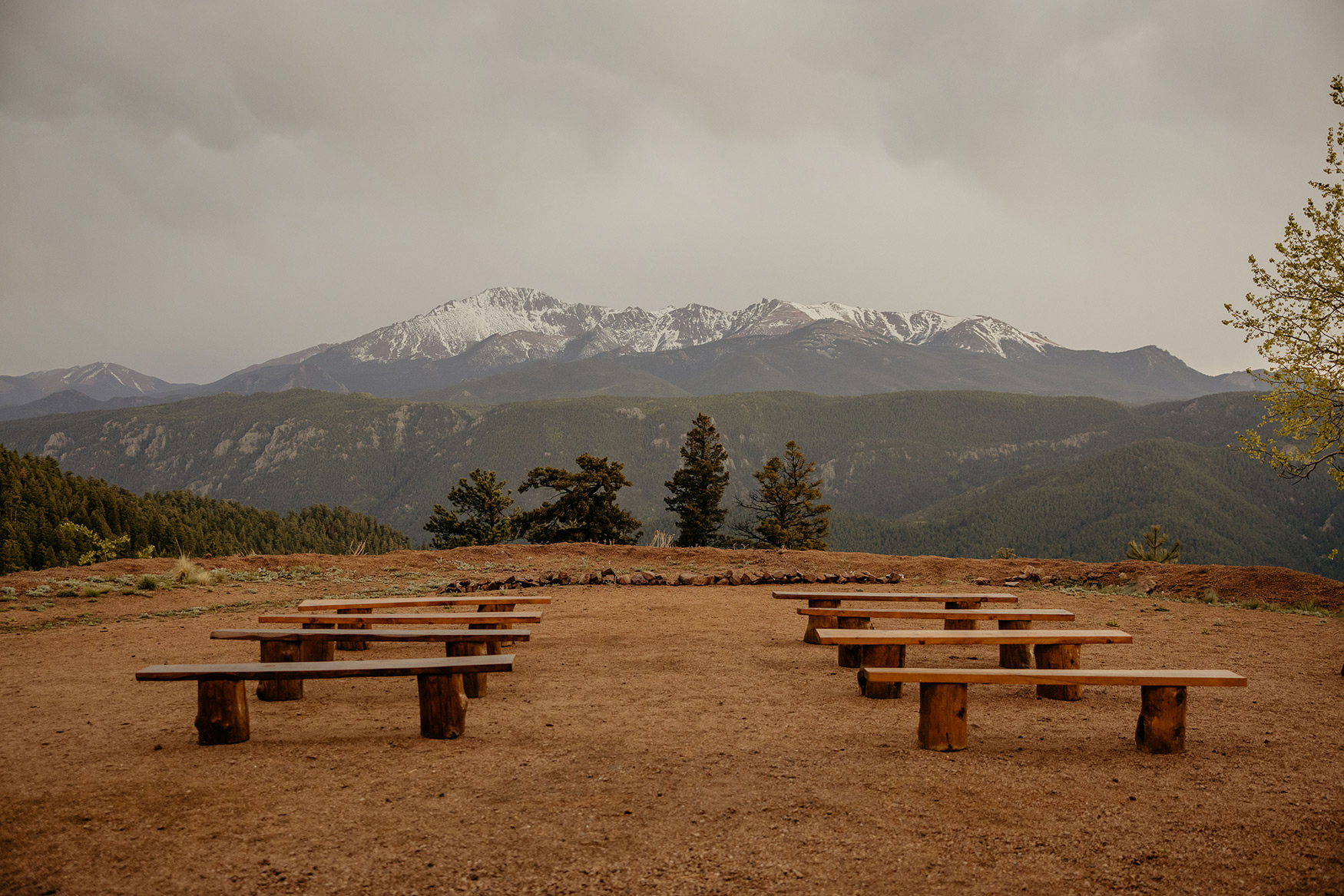 Ceremony benches lined up for wedding with Pikes Peak snowy mountain in background.