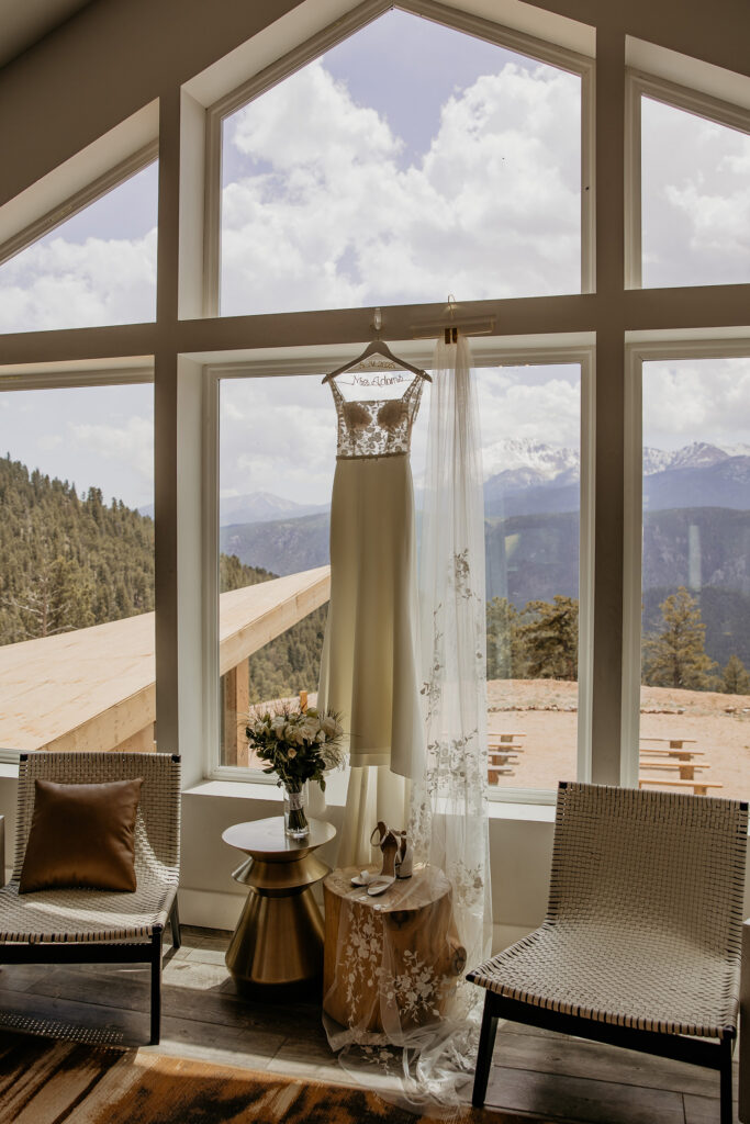 Wedding dress hanging from window at The Summit, a wedding venue in Woodland Park. 