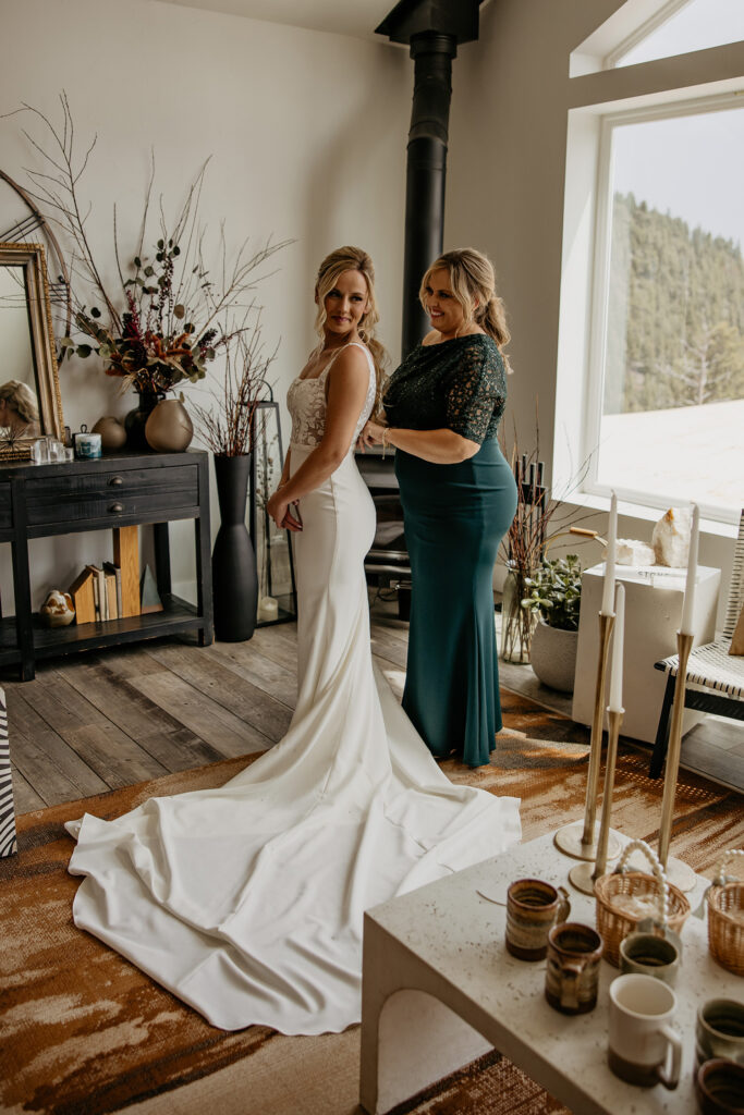 Mother of bride helps bride into wedding dress at The Summit wedding venue in Woodland Park, Colorado.